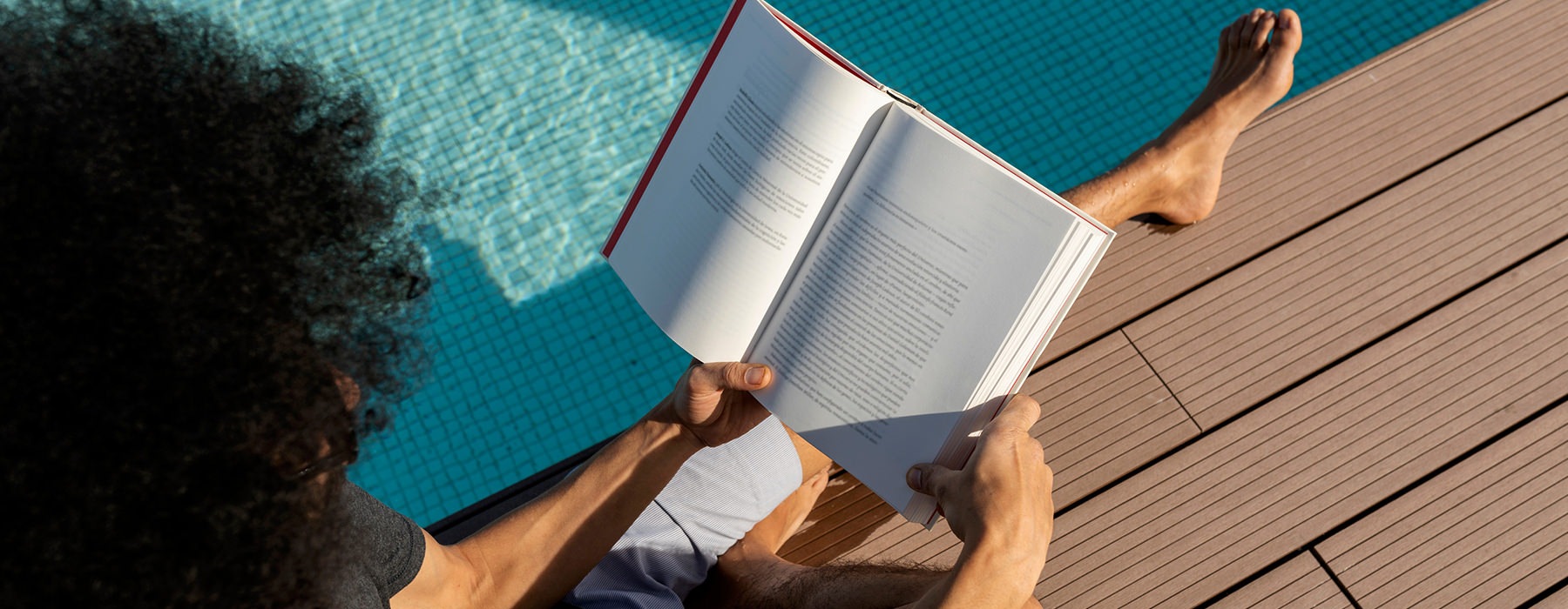 man reading book by pool