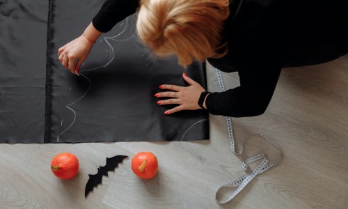 Woman cutting out halloween costume on black paper